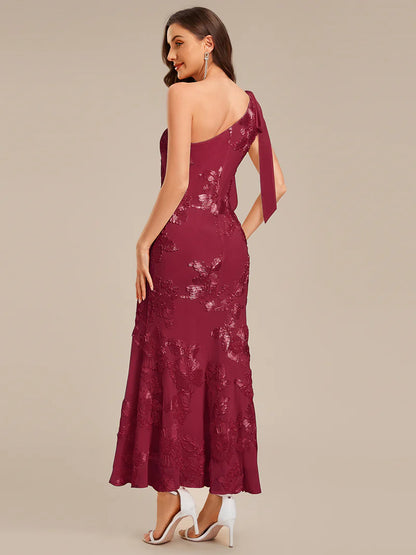 Woman wearing a burgundy lace evening gown with a plain background