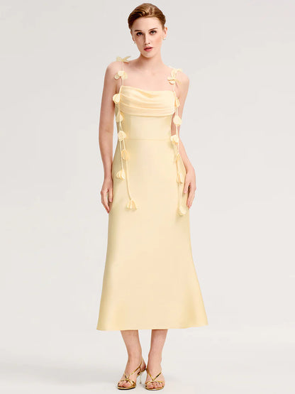 Woman wearing a  yellow two shoulder dress with floral details on a white background