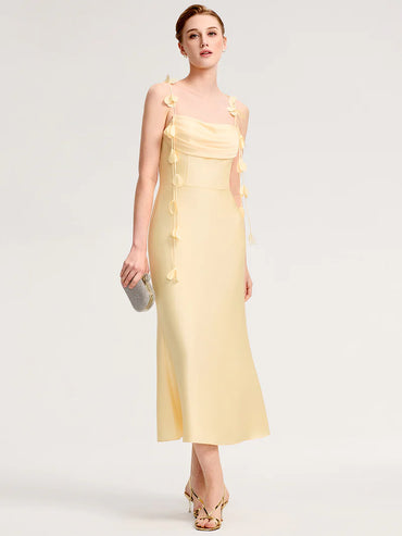 Woman wearing a yellow tshoulder dress with floral details on a white backgroundo 