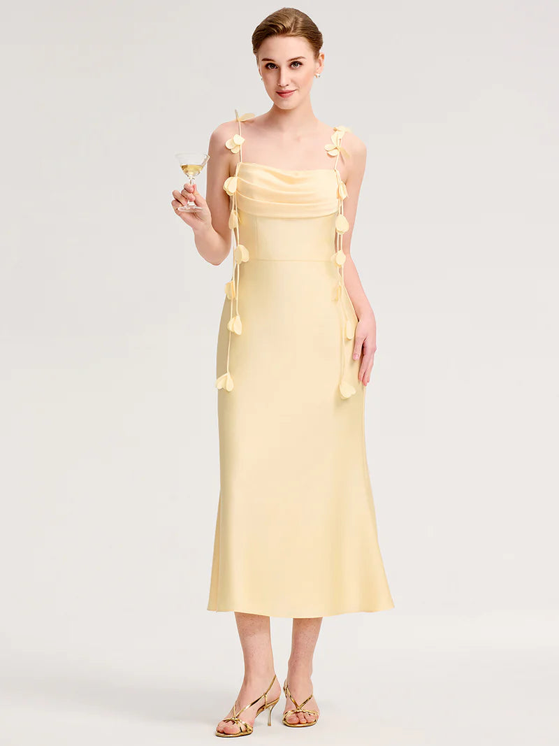 Woman wearing a  yellow dress with floral embellishments on a white background
