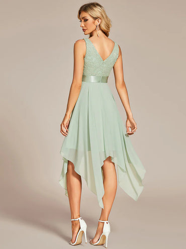 Woman wearing a mint green dress with a high-low hem on a beige background