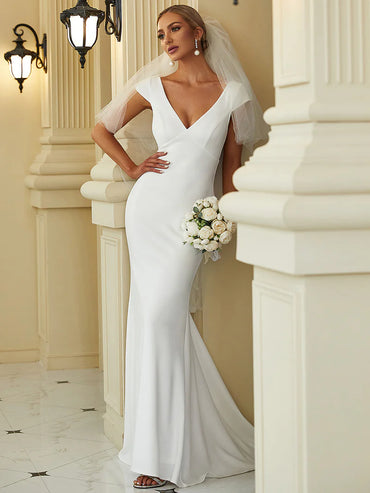 White wedding dress with deep V-neckline, backless design, fishtail silhouette, and sheer cover sleeves